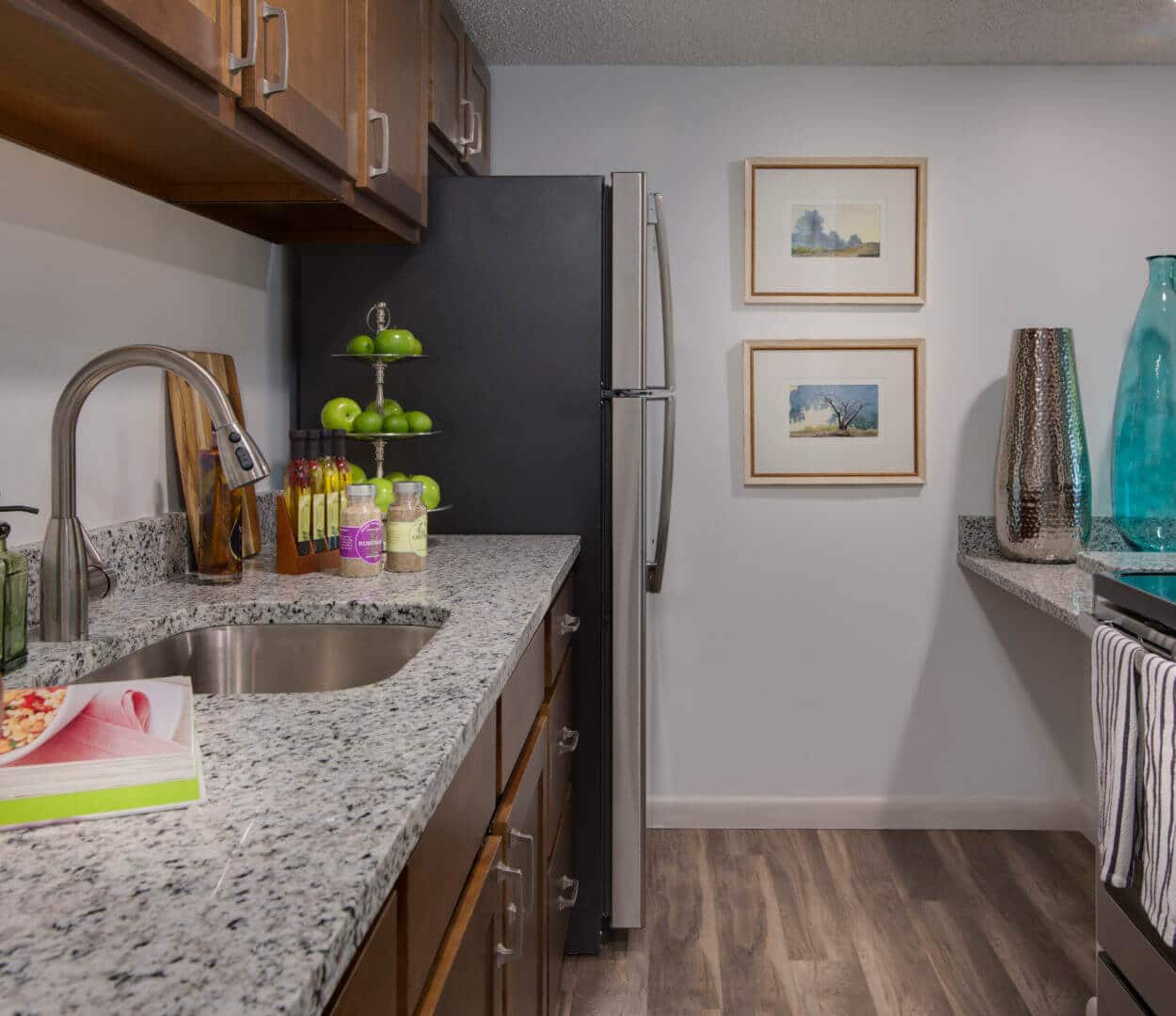 apartment kitchen with granite countertop, refrigerator, stove/oven, blue glass vase