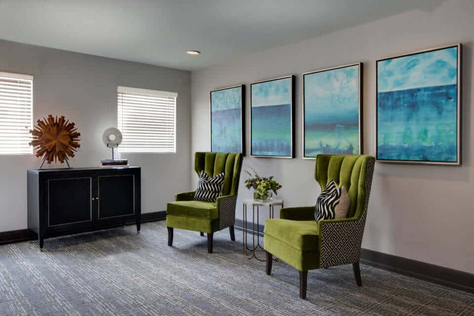 hallway seating with green wingback chairs and blue artwork