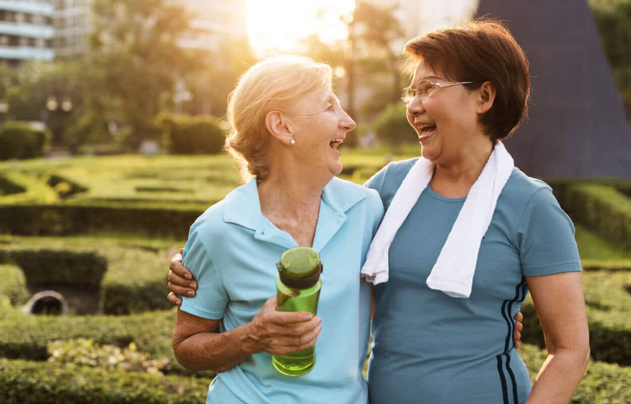 Two senior women embracing and smiling in active wear