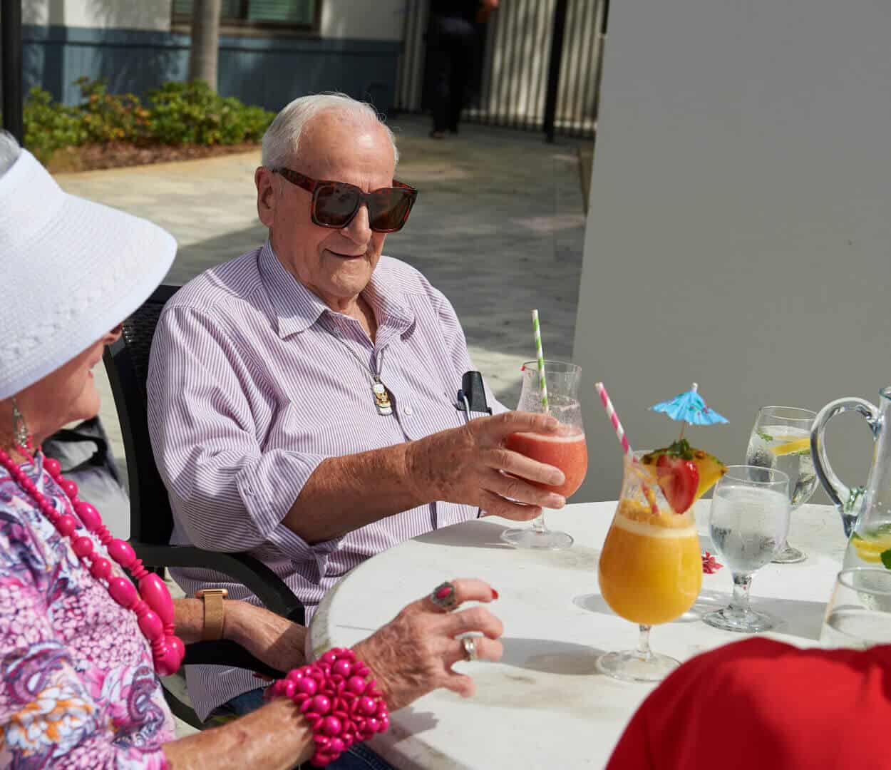 senior residents sitting poolside with cocktails in hand