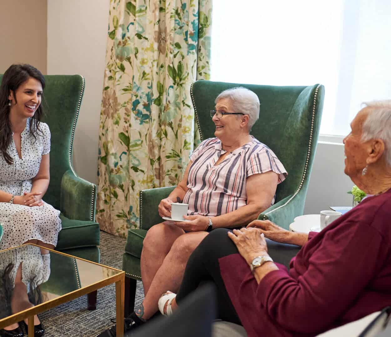 two senior women seated having conversation with young woman