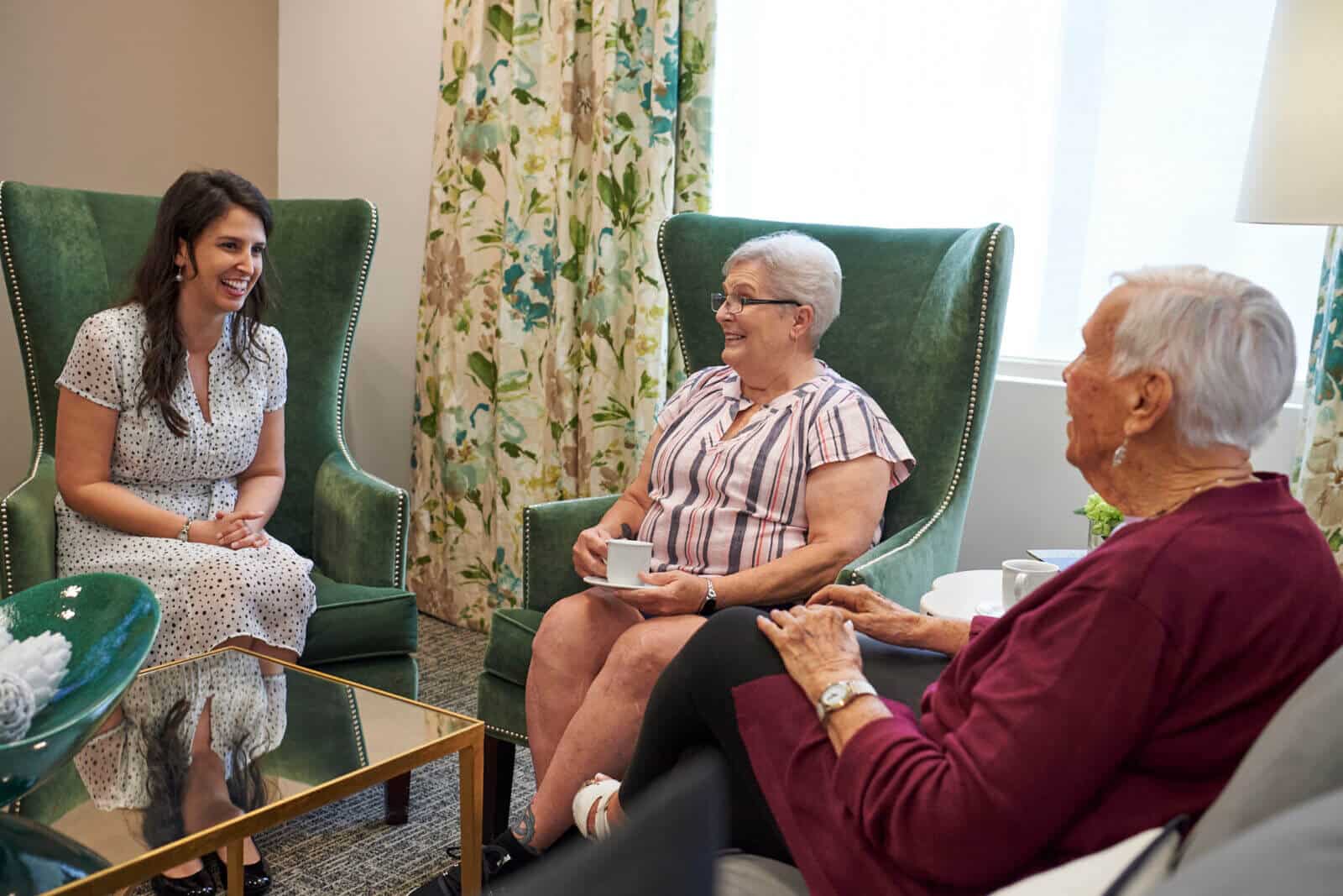 two senior women seated having conversation with young woman