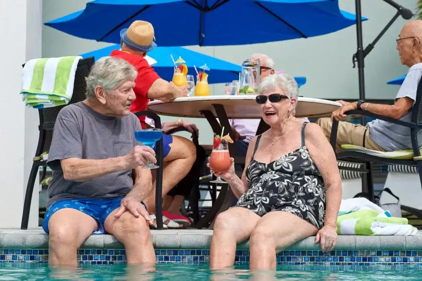 senior residents sitting poolside with cocktails in hand