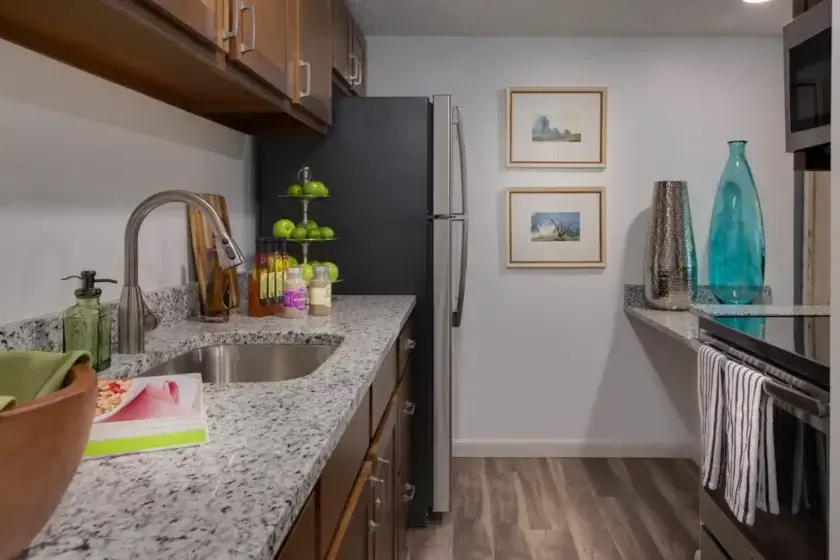 apartment kitchen with granite countertop, fridgerator, stove/oven, blue glass vase